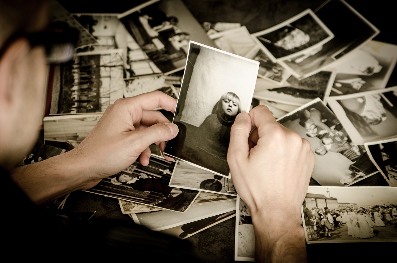 homem com foto antiga na mão sob mesa de fotos antigas